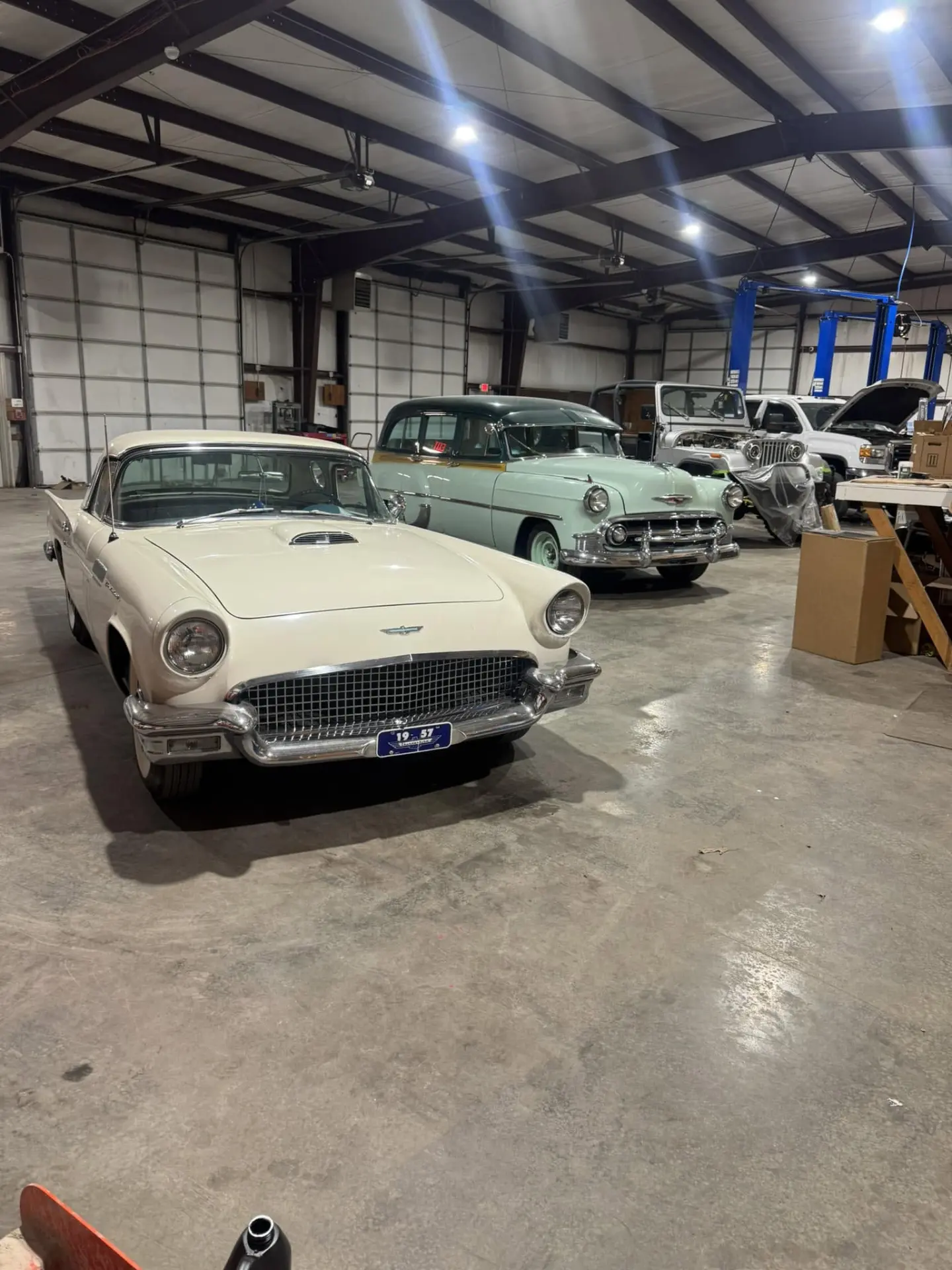 Classic 1957 Ford Thunderbird and vintage Chevrolet inside the All Roads Auto shop