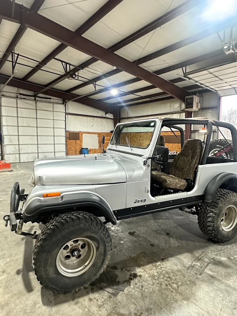 Silver Jeep CJ-7 on oversized tires inside the All Roads Auto shop